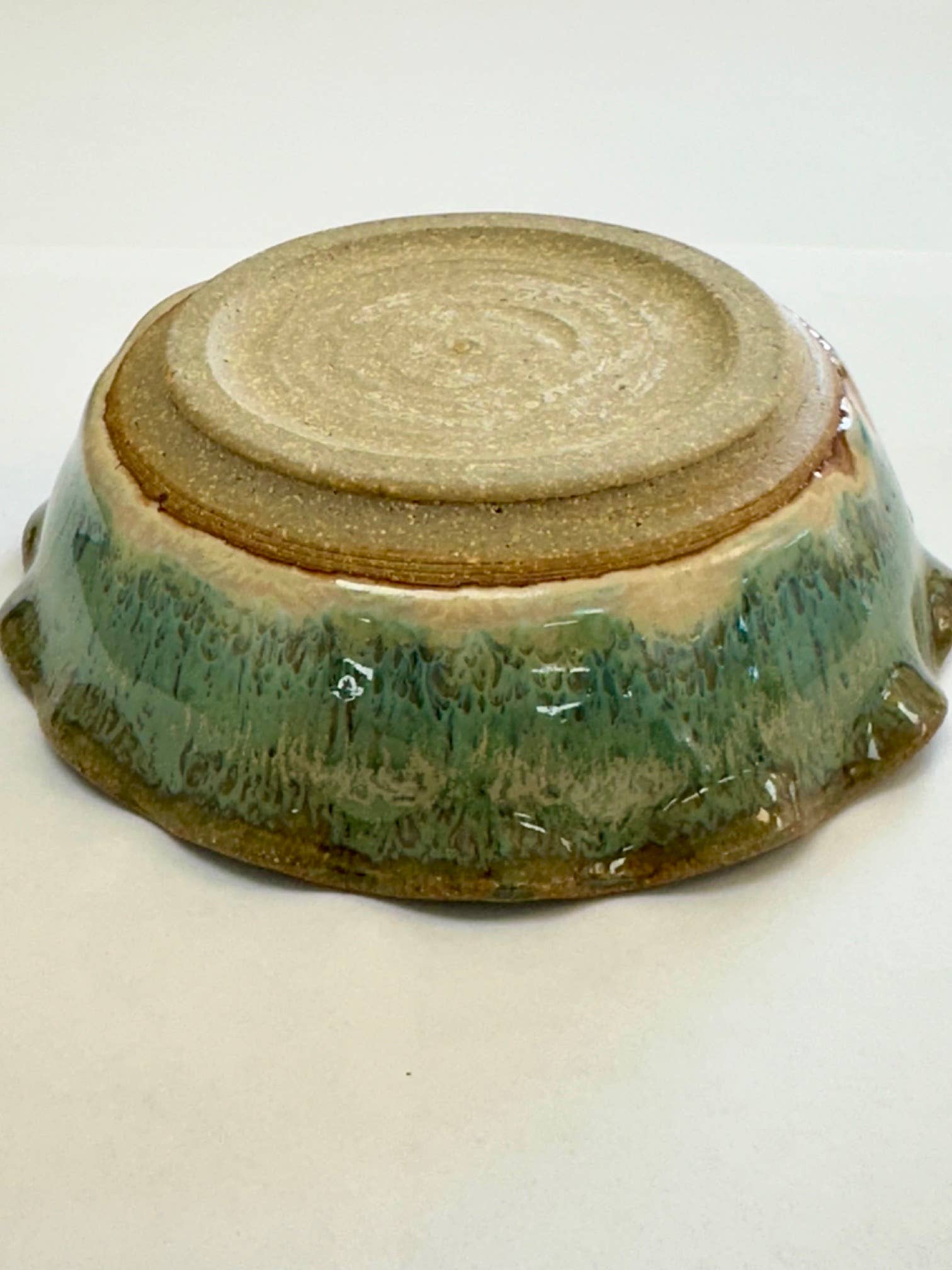 A handmade small stoneware bowl (4 3/8" diameter) crafted from glass and clay, featuring a textured beige base, glossy green and brown glaze, and classic Colorado artistry.