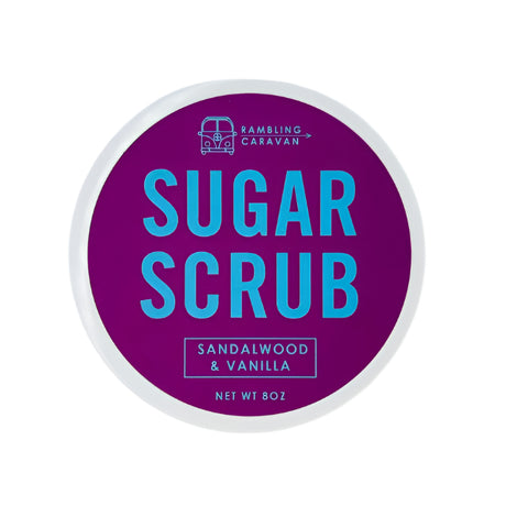 A round container labeled Bath Scrubs: Sugar Scrubs - Sandalwood & Vanilla, Net Wt 8 oz, rests on a purple background with blue text—designed for gentle exfoliation and radiant skin.