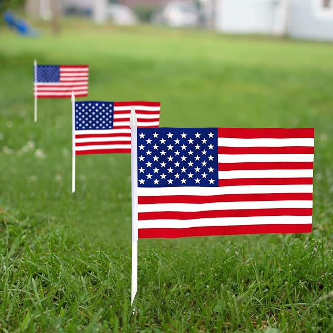 Three USA United States Mini Flags (5x8) on white sticks stand in a row on green grass, their fade-resistant colors vivid against a blurred yard—perfect handheld American flags for patriotic events.