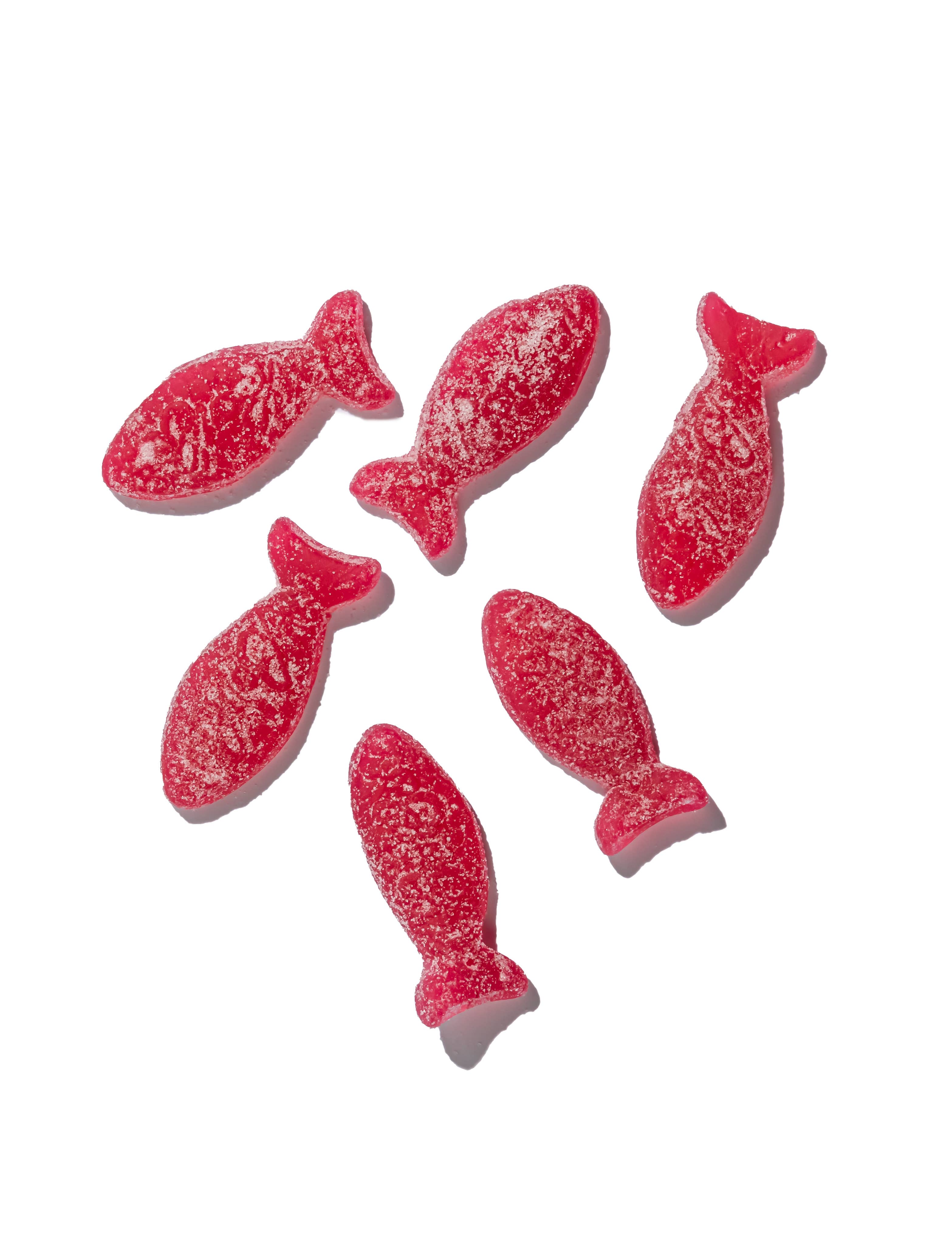 Six sugar-coated, sour wild strawberry fish gummies from the Bon Bon collection are artfully arranged on a white background. These gluten-free candies promise a sweet and tangy delight.