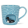 The Wavy Aqua Mug with Loon in Recess (4"H, 14oz) features handcrafted ceramic, a textured wave pattern, and a detailed black-and-white loon figurine near the base—making it an ideal nature-inspired gift.