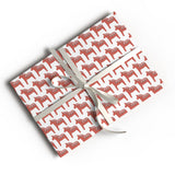 A rectangular gift box wrapped in Juniper Blue's Swedish Dala Horse Gift Wrap (glossy, 2 sheets, 20"x29" each) tied with a white ribbon and bow, displays charming Scandinavian style on a white surface.
