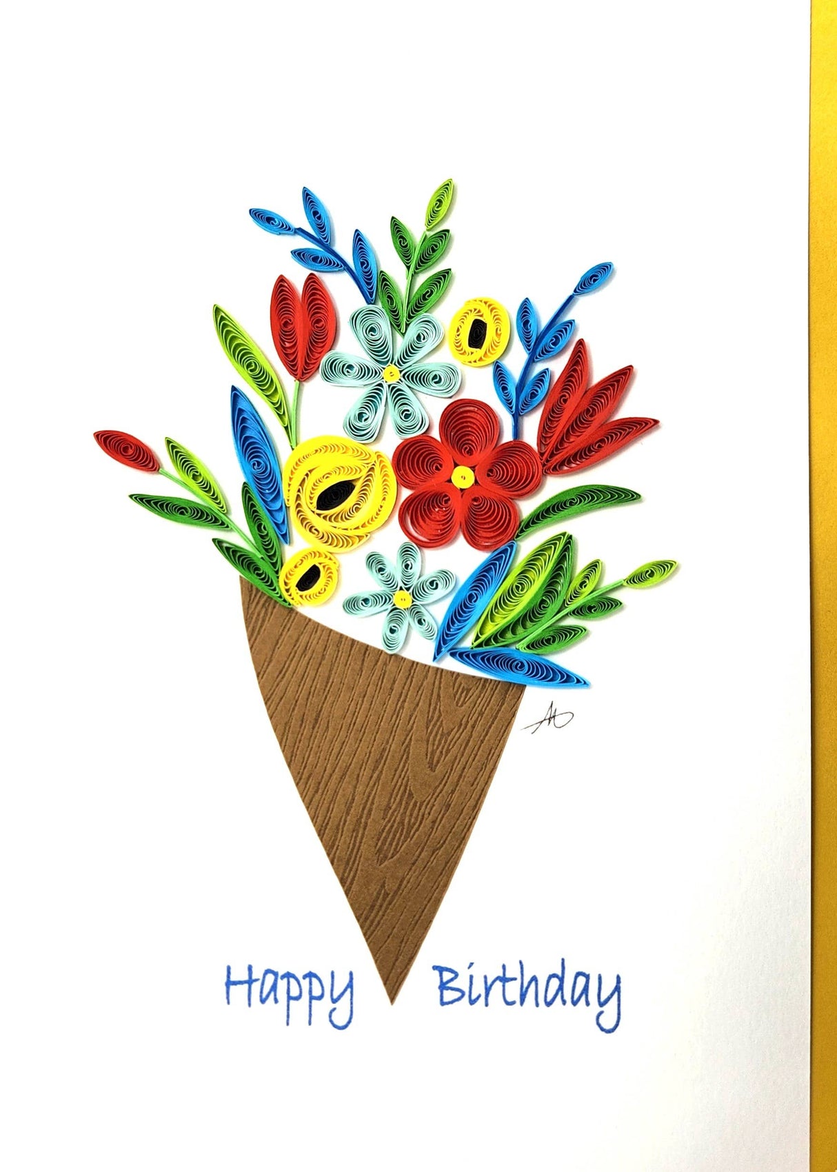 A unique handmade 5x7 Happy Birthday card featuring a quilled blue flower bouquet in a brown cone, blank inside for personalization, with "Happy Birthday" in blue text and a yellow envelope included.
