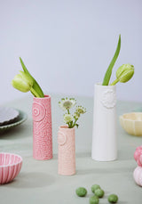Three handmade Nordic ceramic vases in pink, light pink, and white with embossed floral patterns, holding fresh flowers.