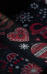 Black fabric featuring a woven Nordic-style pattern of red and white hearts, Dala horses, and Scandinavian star motifs.