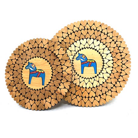 Two round wooden trivets with laser-cut heart-shaped designs feature a central blue Swedish Dala Horse, as per the Trivet: Swedish Dala Horse - Blue Wooden Trivet with Laser Cut Hearts product.