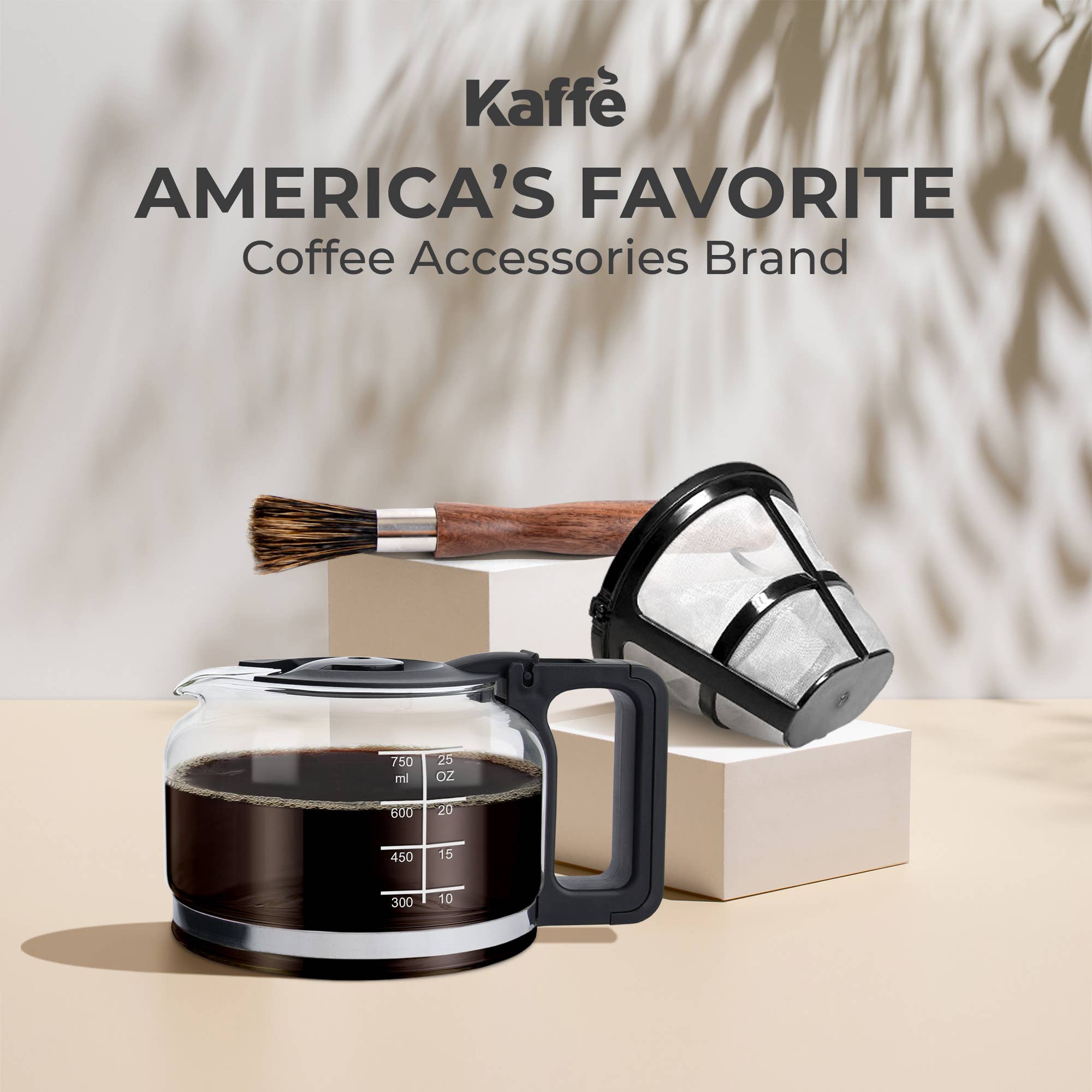 A Kaffe Universal Permanent Coffee Filter for 5-cup coffee makers, a glass carafe filled with coffee, and a cleaning brush are displayed on neutral blocks with "Kaffè America's Favorite Coffee Accessories Brand" above them.