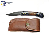 The Knife: Damascus Steel Pocket knife features a decorated Damascus steel blade and walnut wood handle, displayed next to a stitched brown leather sheath with a brass button. The Titan International Knives logo is shown in the corner.