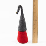 Scandinavian gnome doll made of wool with a tall gray hat and red body shown next to a wooden ruler indicating a height of approximately 8 inches.