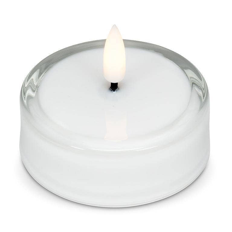 White LED tea light inside a clear glass holder with a flickering flame.