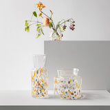 Three Meadow vases with multicolored confetti patterns, one holding a small bouquet of wildflowers.
