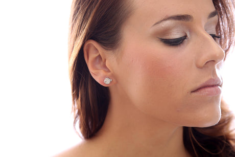 Close-up of a womans profile with neutral makeup, eyes closed, and hair partly visible. She wears sparkling Fish Shaped Swarovski® Crystal Silver Stud Earrings.