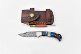 The Damascus Steel Pocket Knife features a patterned blade and multicolored handle, displayed below a brown leather sheath with decorative stitching and an included sharpening rod.