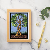 Card: Together Forever Tree by Sarah Angst (5x7) features a stylized tree with heart-shaped foliage. Displayed on marble with a gold pen, paper clips, and eucalyptus leaves. Made in America.