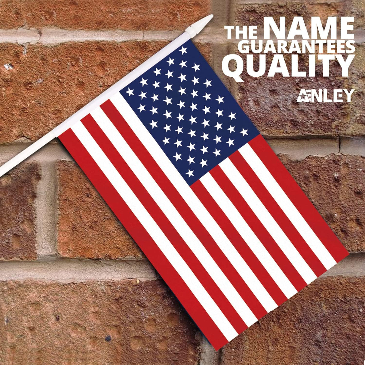 A USA United States Mini Flag (5x8) with fade-resistant colors on a white stick is mounted on a brick wall. The top right corner displays: THE NAME GUARANTEES QUALITY ANLEY.