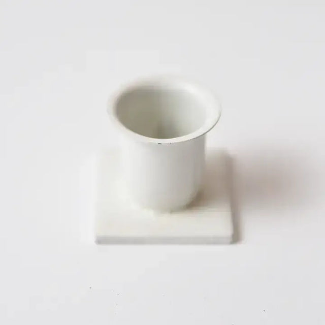 The Candle Holder: White Iron Square Taper Holder features a small white iron design with a square base, displayed on a plain white background.