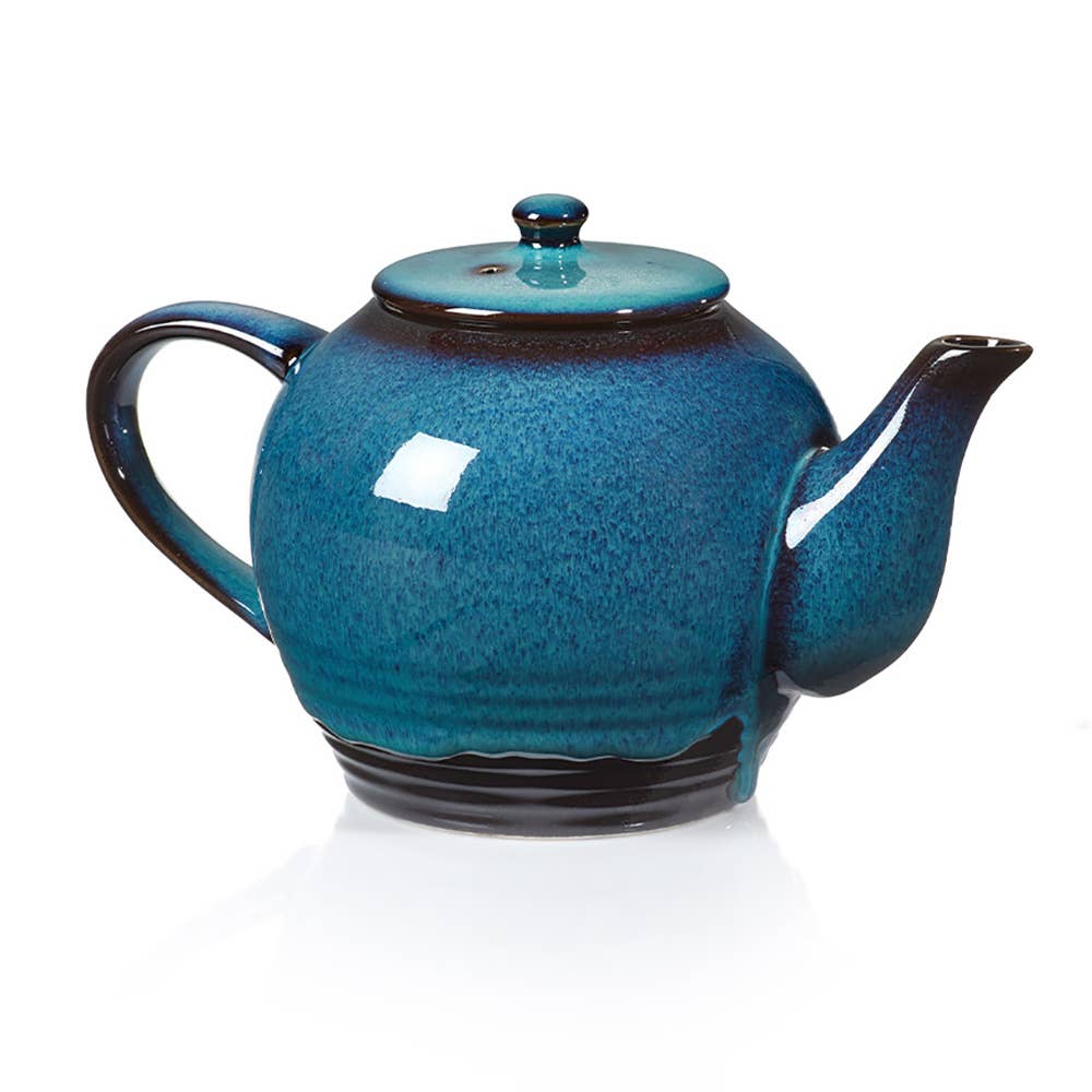 The Tea Pot: Lake Life Ceramic Tea Infuser in blue ceramic, with a glossy finish, curved spout, and rounded handle, evokes lake life tranquility. This handmade teapot adds charm when placed on a white background.