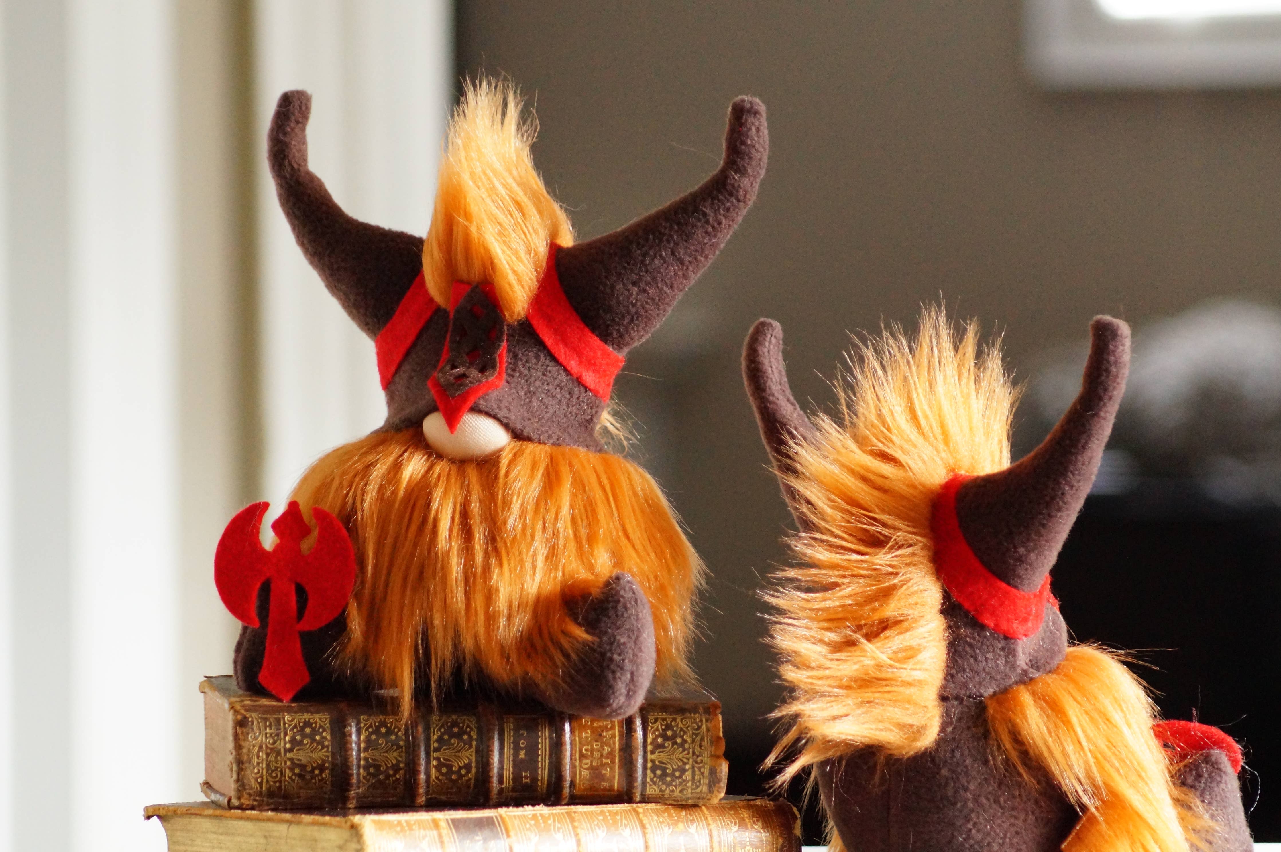 Two Viking Gnomes, characterized by their warrior-like appearance with orange beards and horned helmets, sit atop a stack of old books.