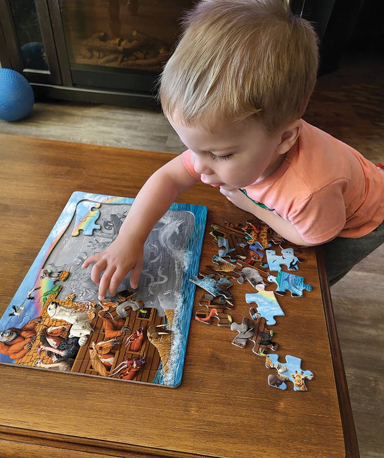 A child focuses on assembling the 35-piece Puzzle: Voyage of the Ark (Tray) on a wooden table.