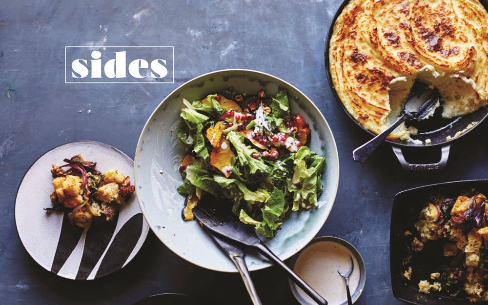 In this delightful scene inspired by the "Book: Potluck," a table showcases a refreshing bowl of salad, a cast iron skillet filled with a gluten-free potato creation, a plate featuring roasted vegetables, and a small bowl brimming with dressing. The inviting word "Sides" takes its place in the top left corner, encouraging all to savor these modern dishes.