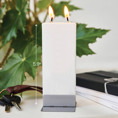 The Candle: Café Terrace - Flat Candle by Van Gogh is a rectangular, drip-resistant white candle with two flames on a silver base, measuring 5.9 inches tall. Keys, a book, and green leaves appear in the background.
