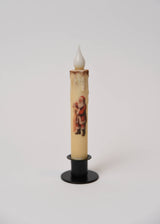Cream-colored LED taper candle with a Santa Claus graphic, set in a black stand.