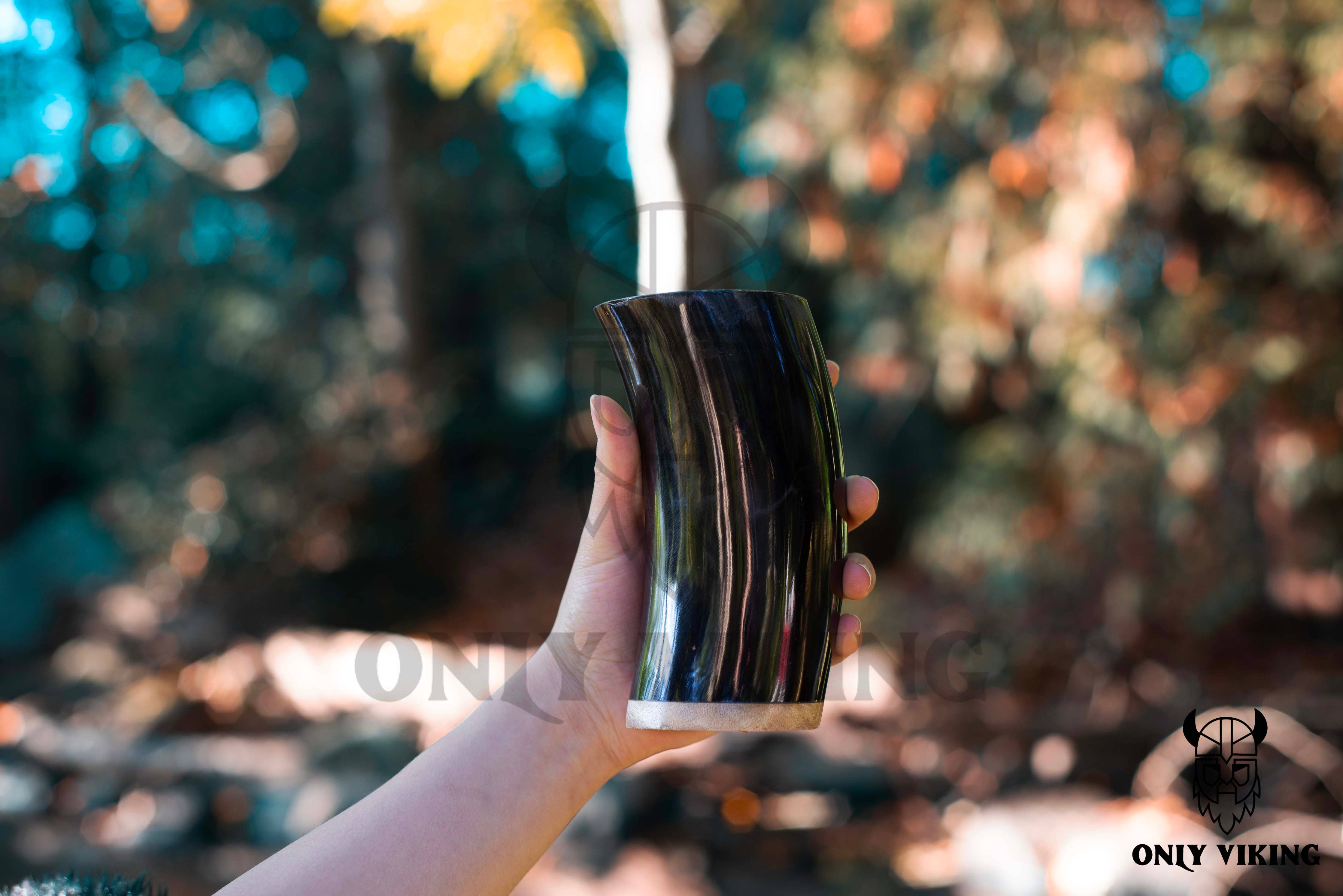 A hand holds the Drinking Horn: Beer Stein 6 Inch outdoors, surrounded by trees and sunlight. The Only Viking logo is visible in the image.