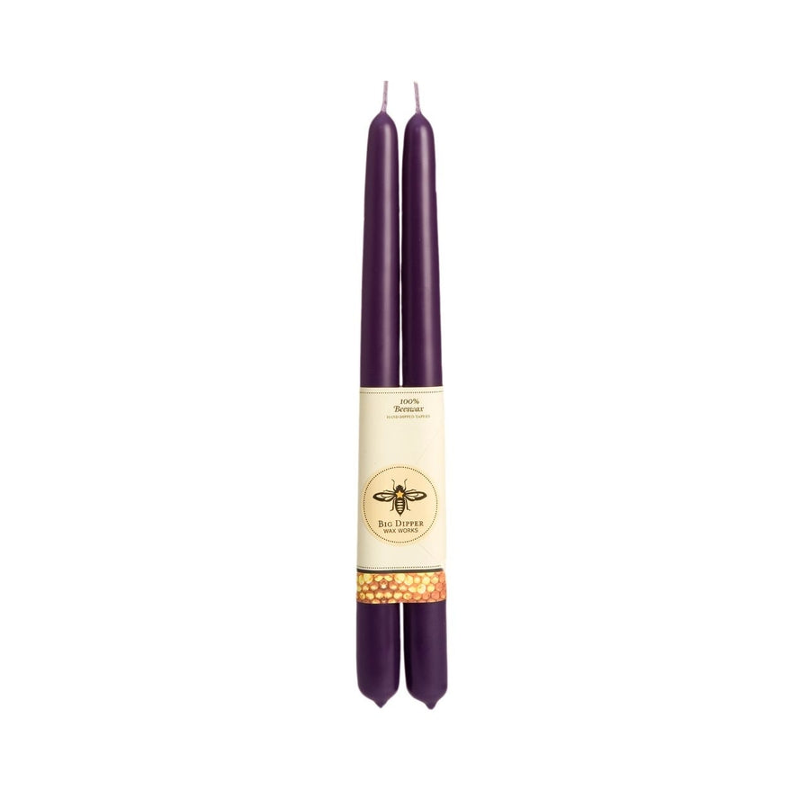 The Candle: Big Dipper Wax Works 100% Beeswax Taper Candle Pair includes two tall, dark purple tapers with a beige label adorned with a bee design, adding handcrafted elegance and charm to any setting.