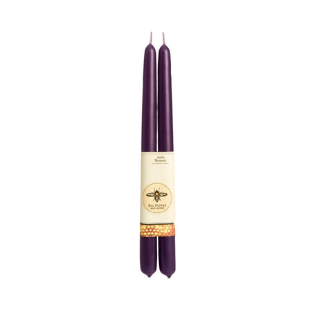 The Candle: Big Dipper Wax Works 100% Beeswax Taper Candle Pair includes two tall, dark purple tapers with a beige label adorned with a bee design, adding handcrafted elegance and charm to any setting.