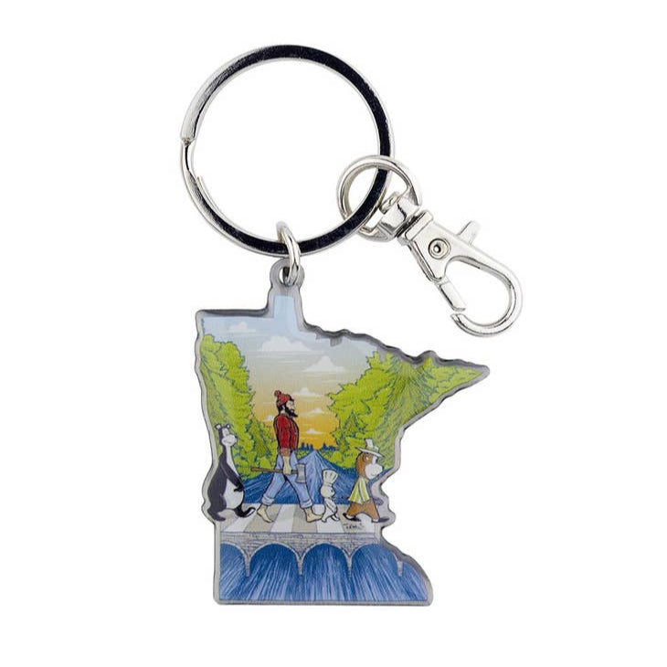 This Keychain: Abbey Road Turman features a vibrant design by Adam Turman, depicting a person and animals harmoniously walking through the picturesque Minnesota landscape, embodying the spirit of adventure and artistry.