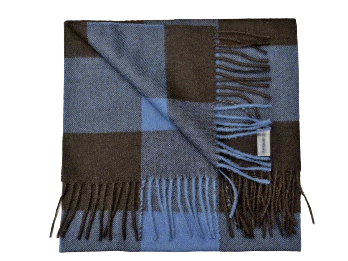 A folded luxury square scarf in blue plaid, crafted from 100% baby alpaca, featuring fringed edges.