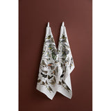 Two 100% organic cotton Garden Birds tea towels (19x27) by Carl Christian Tofte for Koustrupco hang on hooks against a brown wall.