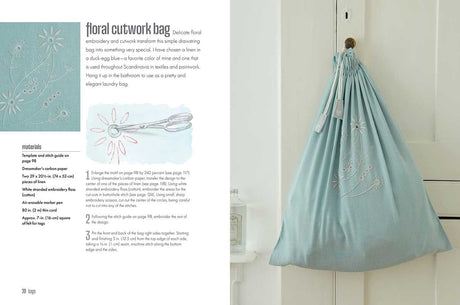 A light blue drawstring bag with white floral embroidery, inspired by Scandinavian design, hangs on a white door; the project is featured in Scandi Needlecraft: 35 Step-by-step Projects to Make by Clare Youngs (Paperback, 128 pages).
