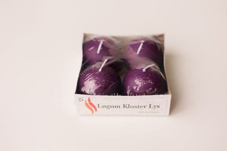 Four purple candles in a white box labeled “Løgum Kloster Lys,” wrapped in clear plastic, set on a white background.