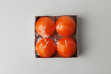 A set of four 2.5" Logum Kloster Lys ball candles by Talla Imports comes in a square box, each orange candle individually wrapped—ideal hygge accents for cozy spaces.