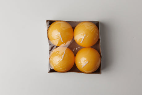 A cardboard box of Logum Kloster Lys 2.5 yellow ball candles (4 pack), wrapped in clear plastic, viewed from above against a light background.