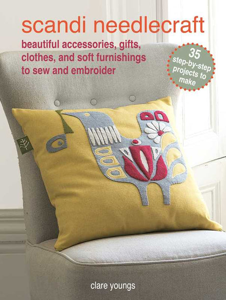 A yellow cushion with a stylized bird, echoing Scandinavian design, rests on a grey chair; above is the book Scandi Needlecraft: 35 step-by-step projects to make by Clare Youngs, paperback, 128 pages.