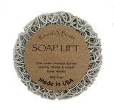 Explore the Soap Lift: Soap Saver Round A Bout - Mist, Light Gray, featuring a circular shape with a curly pattern, made from multi-directional bioplastic. This BPA-free product is crafted in the USA and is perfect for placing under soap bars, shampoo bottles, or shaving creams to help organize your shower shelves with ease.