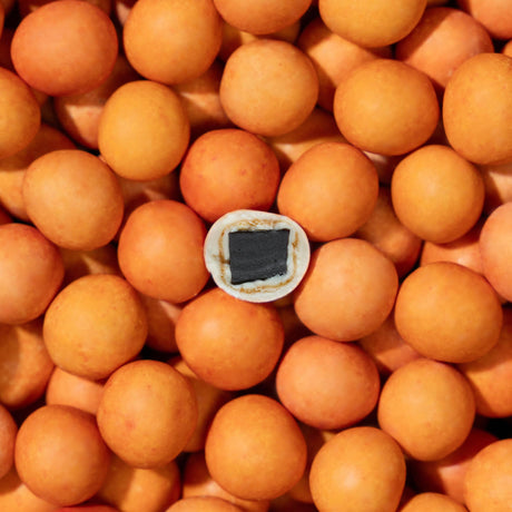 A pile of orange loquats, one halved to reveal a black pit, evokes the appeal of Lakrids By Bülow - Peaches Danish Chocolate Coated Licorice (125g).