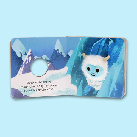 A plush baby yeti finger puppet peeking out of a crystal cave in an interactive baby book.