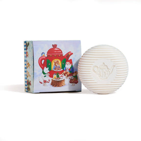 A round, white Gnome Soap Swedish Tea Bar with a teapot design is shown before its festive gift box, which is decorated with animals enjoying tea around a red teapot.