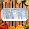 Serving tray featuring a winter forest with snow-covered trees and a full moon, displayed on a wooden table with assorted fruits, peppers, and glassware.
