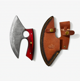 An Alaskan Ulu style blade made of Damascus steel with a red and black diamond wood handle rests beside a brown leather sheath detailed with stitching and brass snap closures.