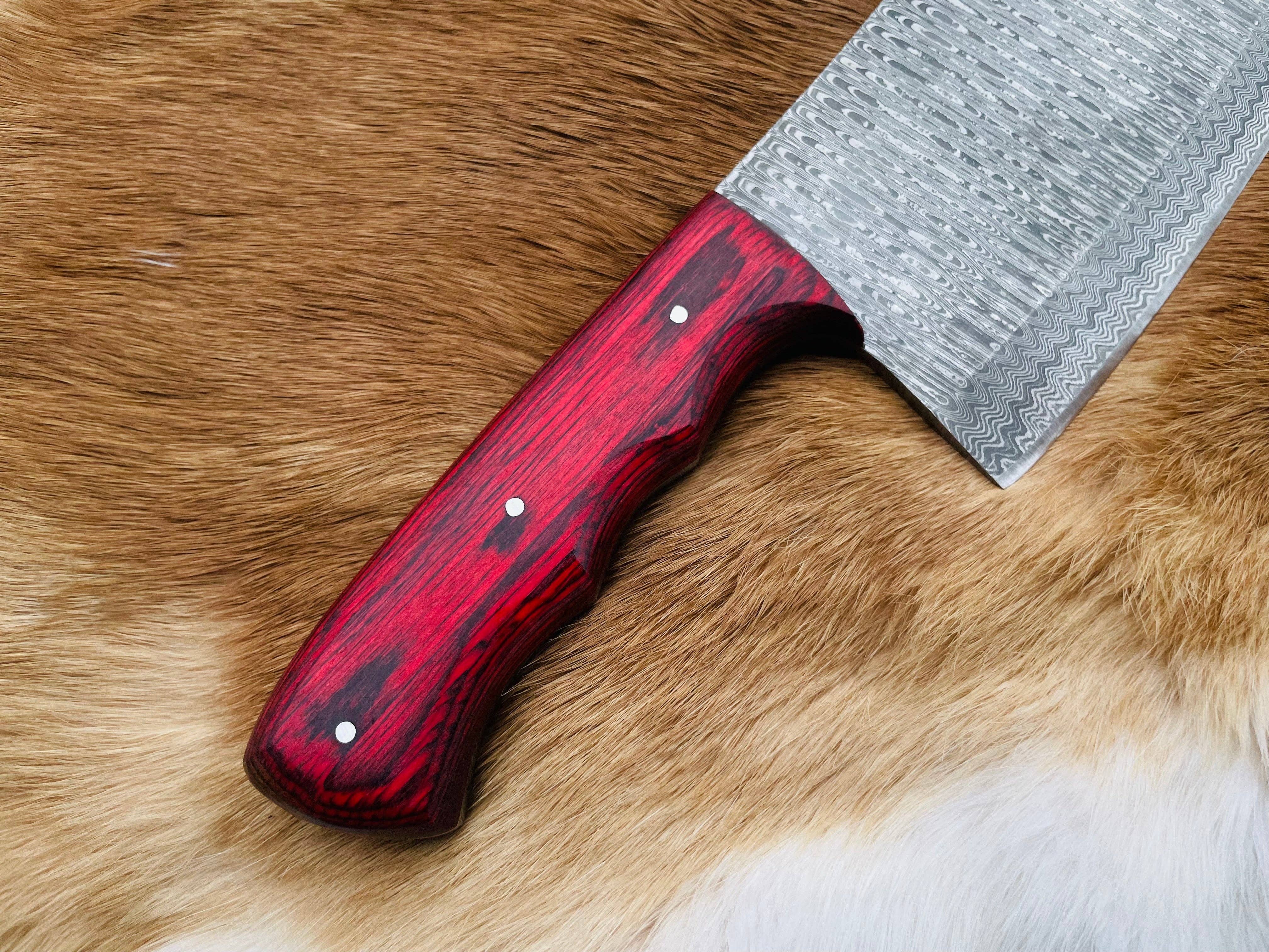 A close-up of the Knife: Custom Damascus Steel Cleaver Red Handle Chinese Cleaver resting on brown and white animal fur.