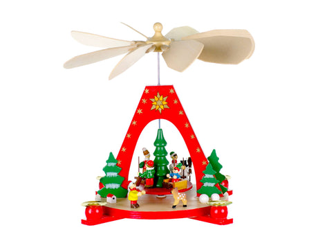 The "Christmas Pyramid: Red Pyramid W/Playing Children" is a decorative wooden piece featuring a red arch with small figures and green Christmas trees. It includes a rotating propeller on top, complemented by red candles, creating a charming candle holder for the festive season.