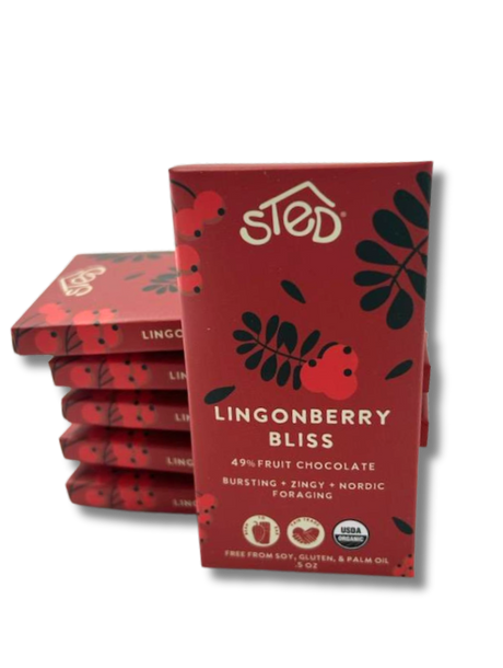 A stack of red packages labeled Sted Lingonberry Bliss with icons for 49% fruit, dairy free, soy free, gluten free, USDA organic, and lingonberry fruit chocolate bar.