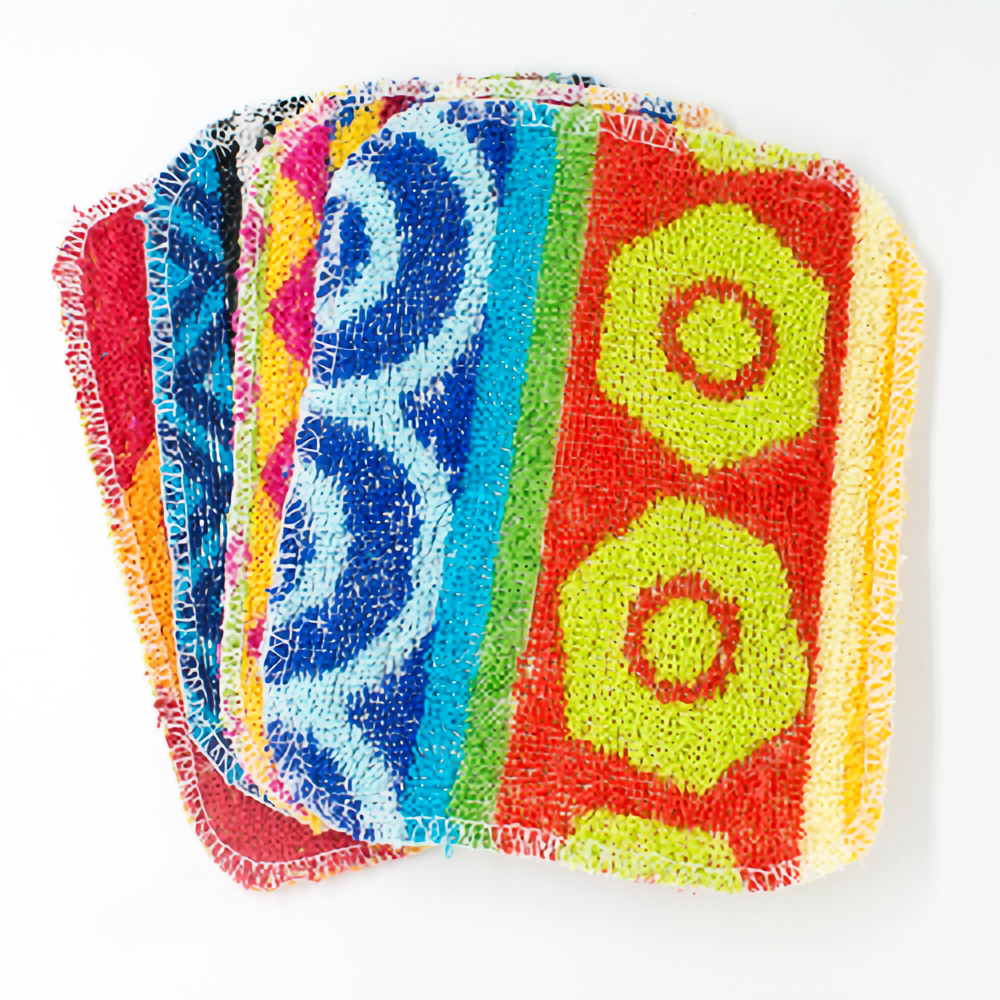 A set of four vibrant Scrub Cloth: Euroscrubby Multi-Purpose Scrubbers, each featuring distinctive geometric patterns and textures, is elegantly arranged on a pristine white background. These environmentally friendly scrubbies are ideal for a variety of cleaning tasks.