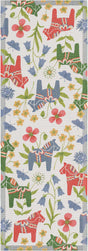 The "Blomsterhast" Flower Horse Table Runner by Ekelund is a rectangular organic cotton runner with red and blue Swedish Dala horses, green leaves, and colorful flowers on a white background.