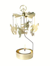 Gold-toned metal rotary candle carousel in a Scandinavian style, featuring hanging doves, a peace sign topper, and a lit tea light candle.