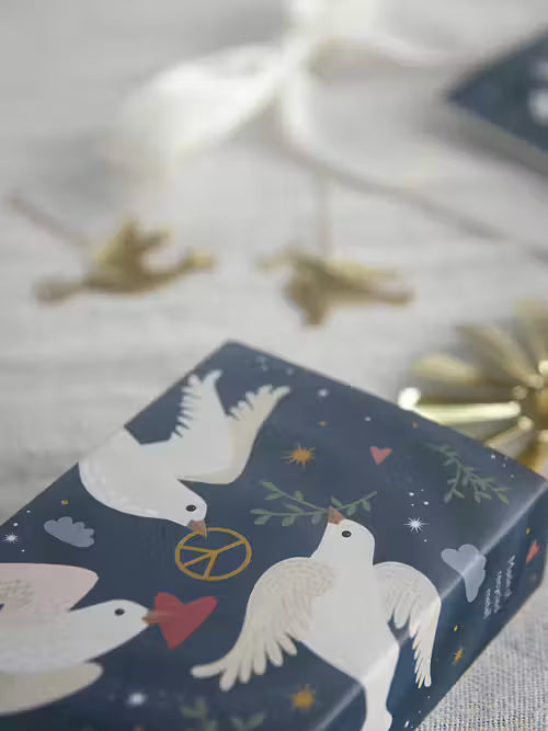 Dark blue wrapping paper with a white Scandinavian-style pattern of doves with olive branches, peace signs, hearts, and stars.